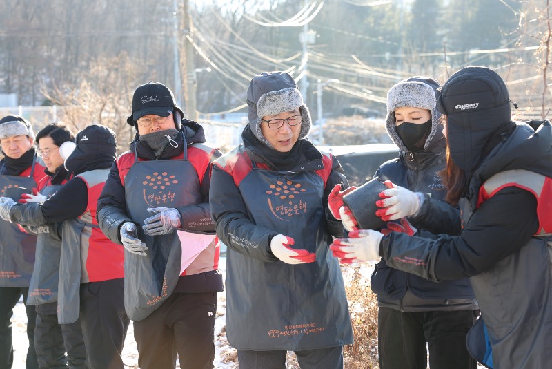 롯데건설 박현철 부회장(오른쪽 세번째)과 배우 정애리(오른쪽 두번째)가 임직원들과 함께 연탄을 나르고 있다